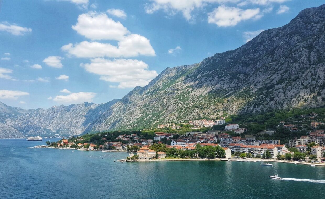 green mountain beside body of water under blue sky during daytime