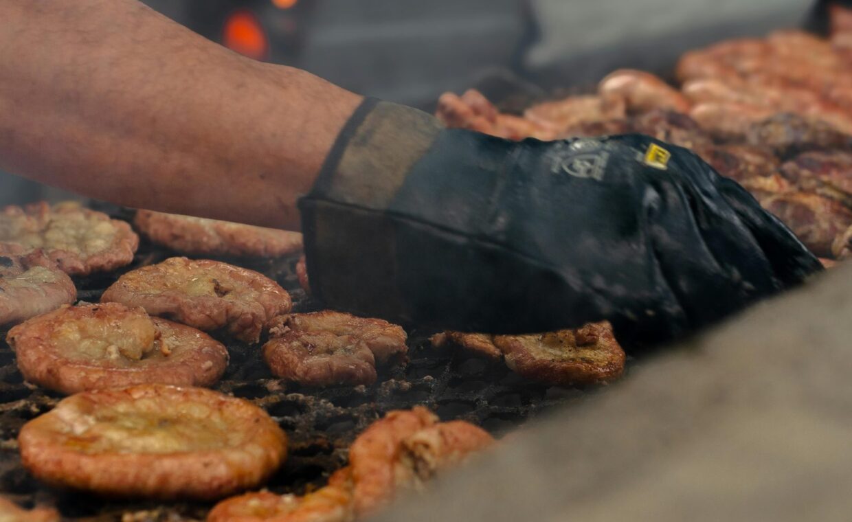 A chef grills traditional meats over an open flame at a BBQ in Buenos Aires, Argentina.