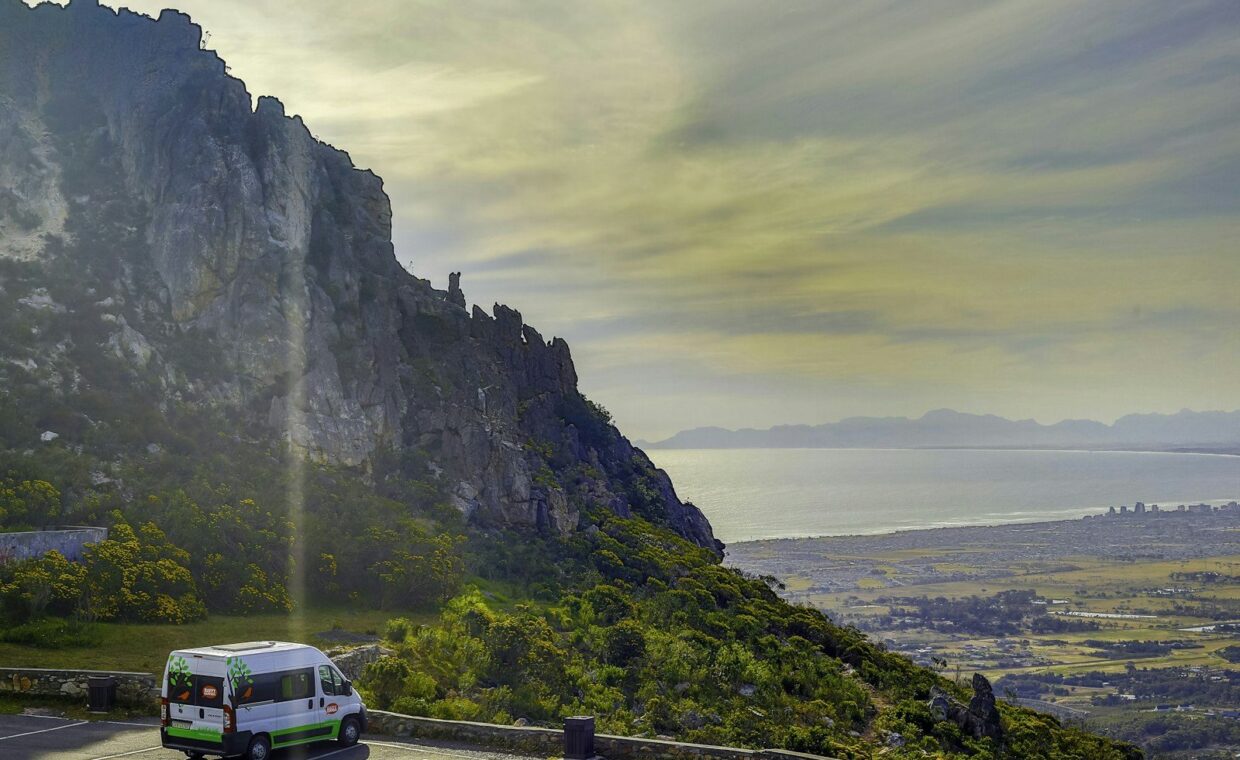 a van driving on a road next to a cliff