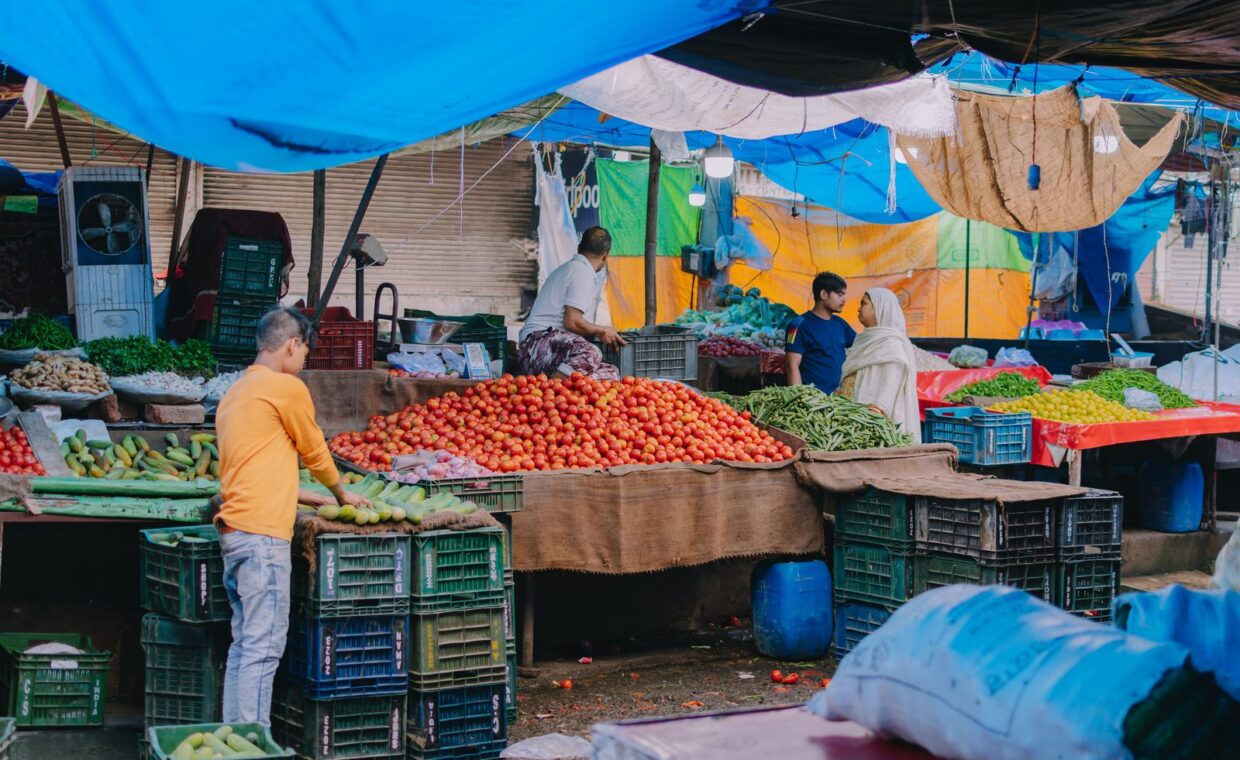 A lively outdoor market scene showcasing vendors selling fresh fruits and vegetables.