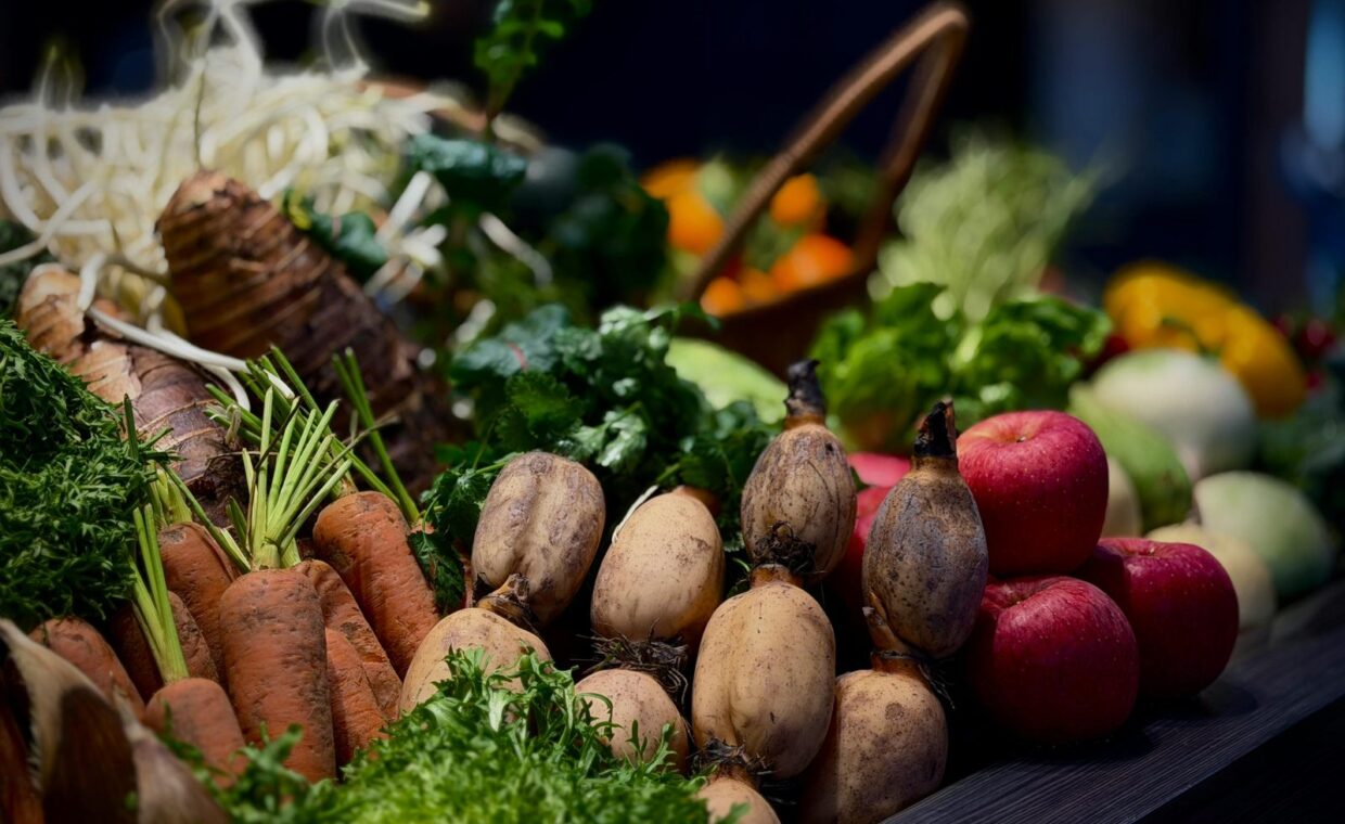 A vibrant display of fresh vegetables and fruits including carrots, apples, and greens.