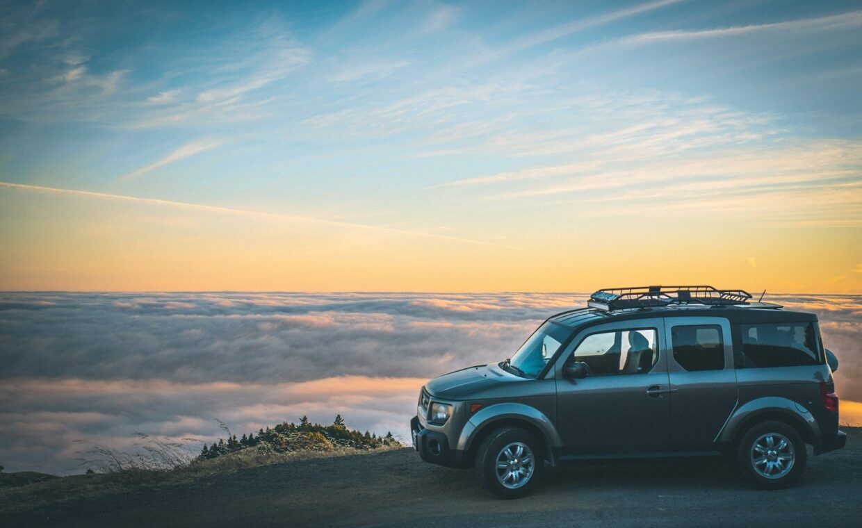 grey SUV beside sea of cloud