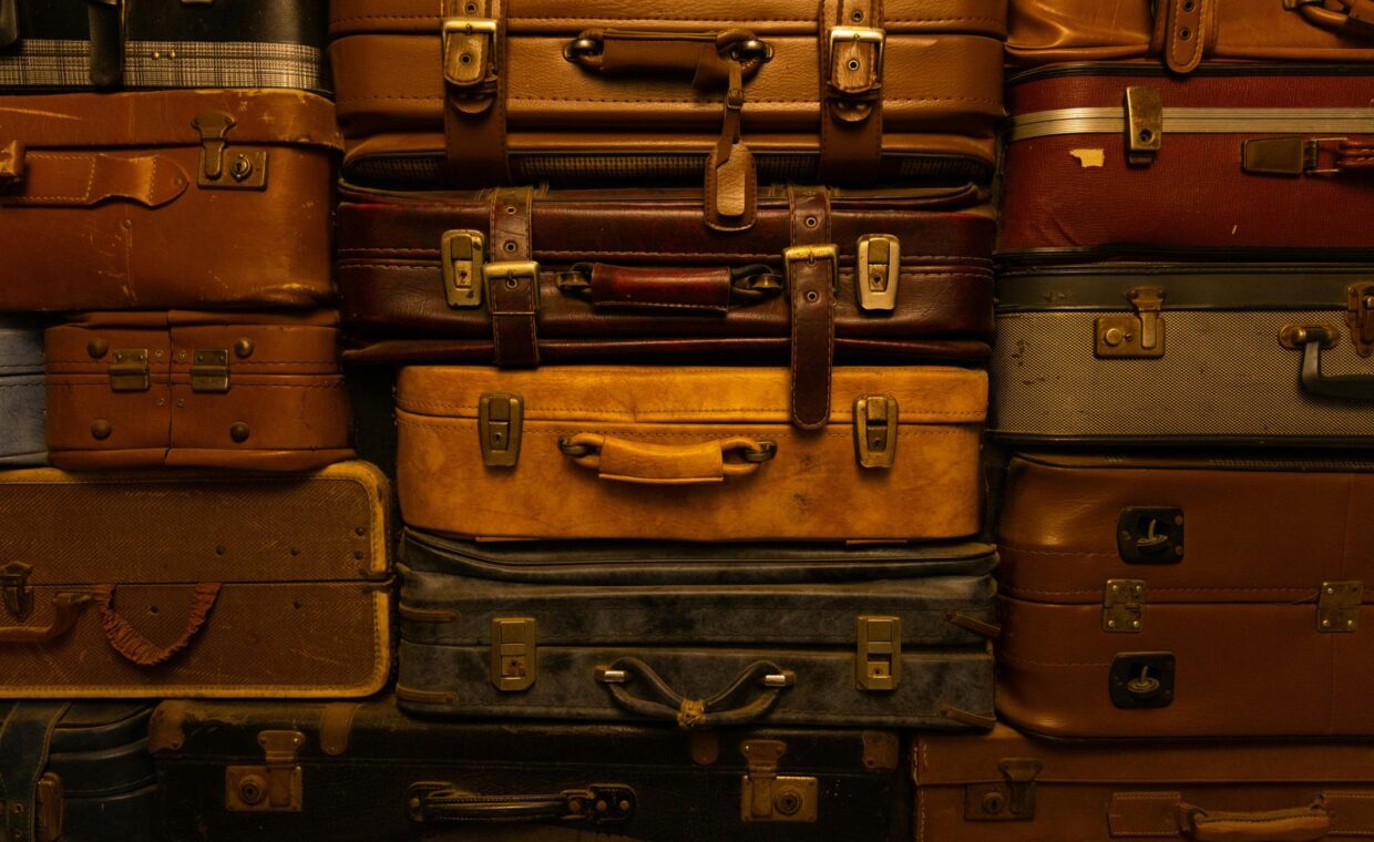 A collection of vintage suitcases stacked together, showcasing a variety of textures and colors.
