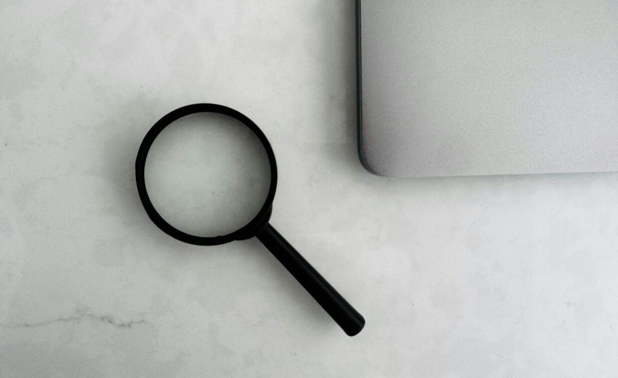 Magnifying glass sits near a laptop on a table.