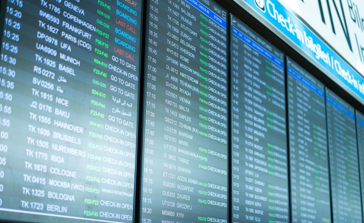 Digital screens display flight information and schedules at an airport terminal.