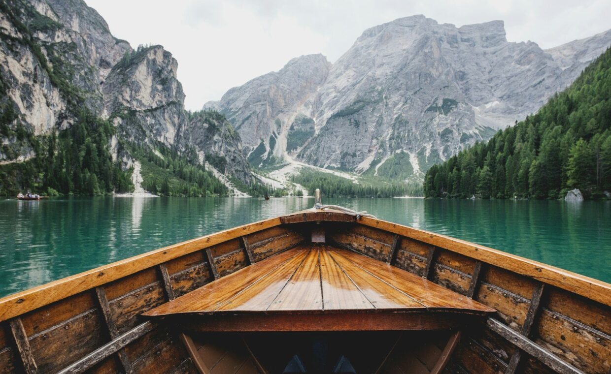 brown wooden boat moving towards the mountain