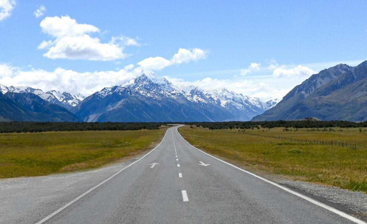 an empty road with mountains in the background