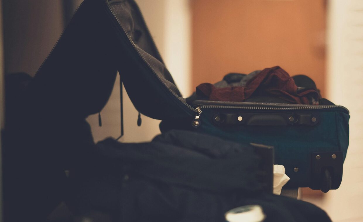 A warm-toned indoor image of an open suitcase with clothes, conveying travel readiness.