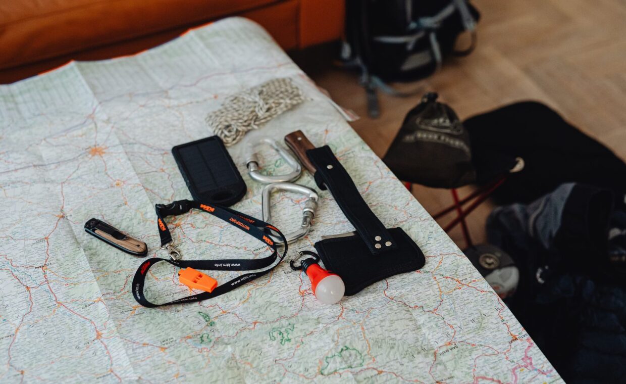 A collection of travel tools and gear laid out on a map, ready for an outdoor adventure.