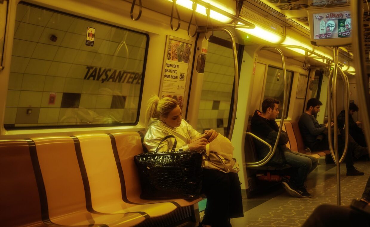 Commuters sitting inside an Istanbul metro train, showcasing a typical urban public transport scene.