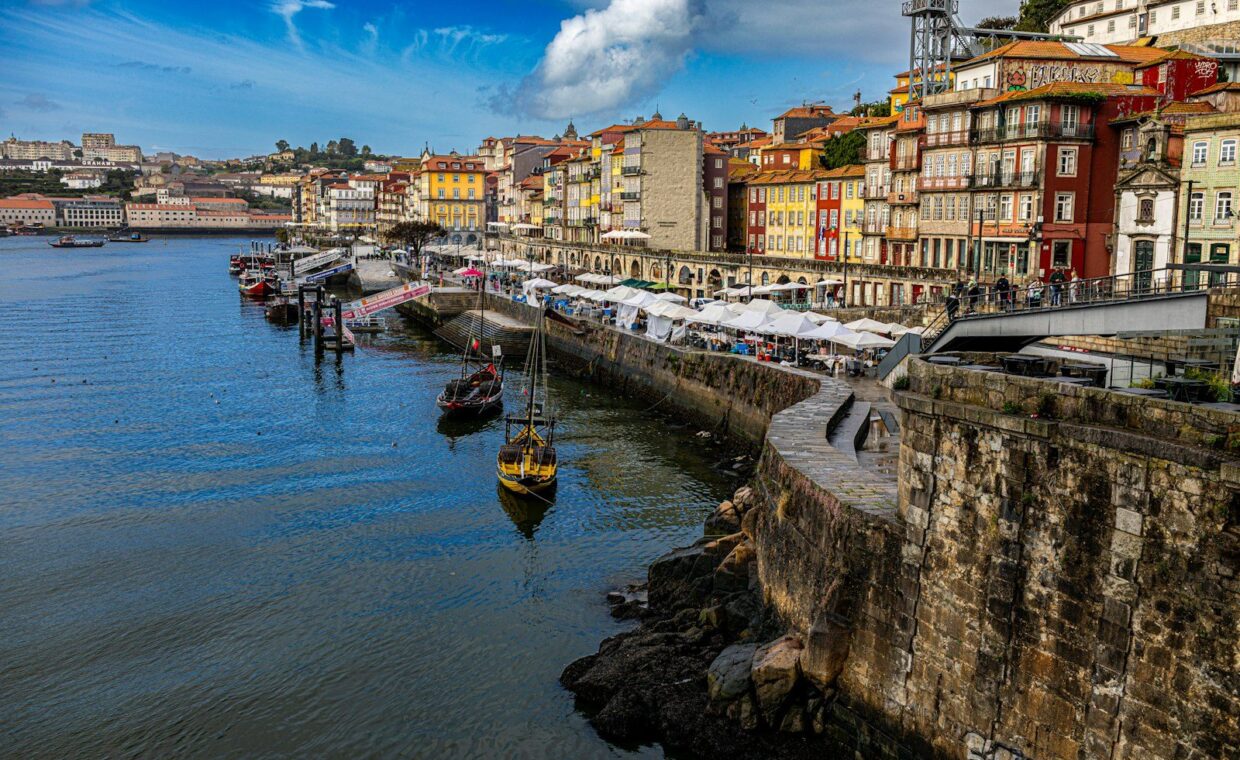 Colorful buildings line a river with boats and stone wall.