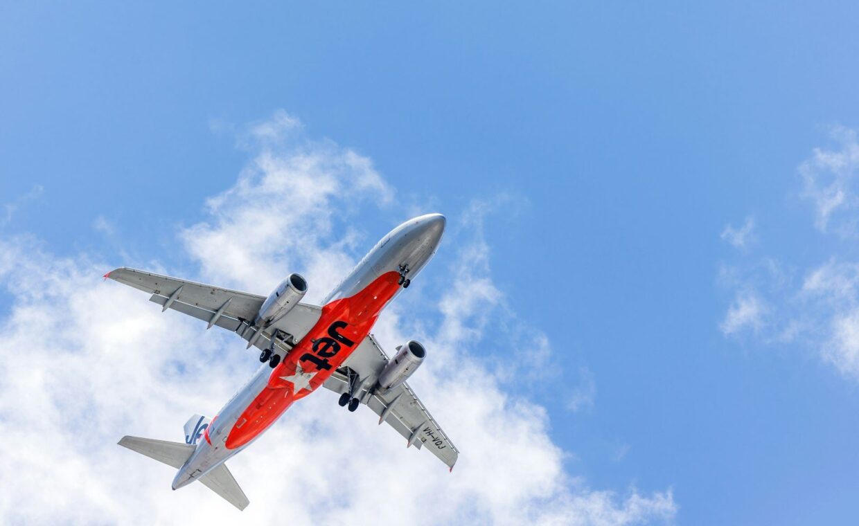 Airplane with orange livery flying in blue sky