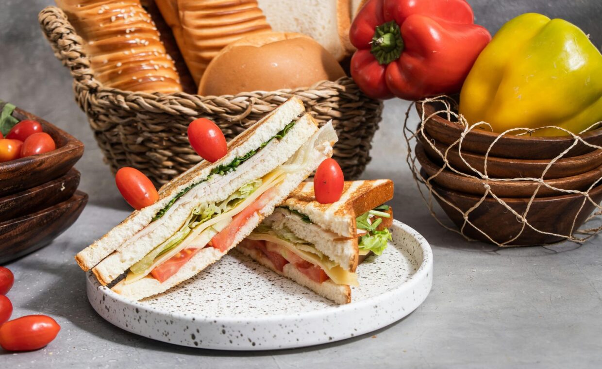 Close-up of a fresh vegetable sandwich with peppers and bread in a rustic setting.