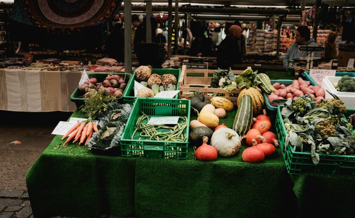 Colorful display of fresh vegetables at an outdoor farmers market stall.